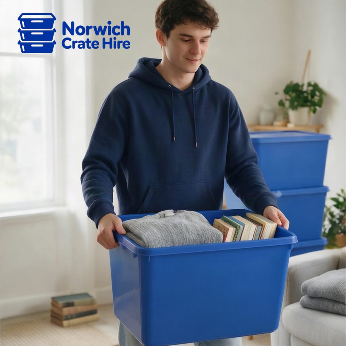 Man carrying a blue Norwich Crate Hire moving crate packed with clothes and books during a home move
